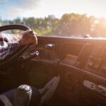 A semi-truck driver keeping their hands on the wheel to ensure their safety while driving down the road