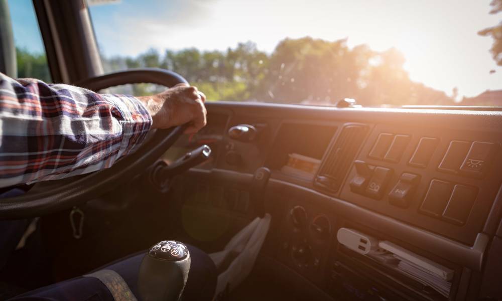 A semi-truck driver keeping their hands on the wheel to ensure their safety while driving down the road