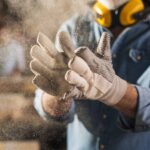 Close-up of dusty work gloves covered in dirt and grime on a construction guy, showing visible signs of heavy use.