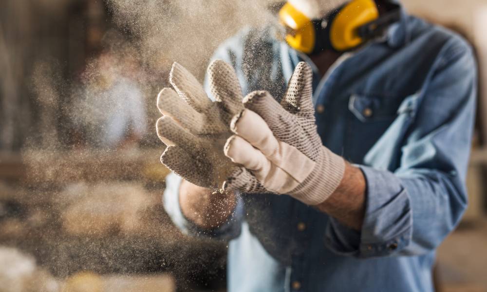 Close-up of dusty work gloves covered in dirt and grime on a construction guy, showing visible signs of heavy use.