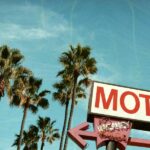 A retro and aged roadside motel sign overlooking palm trees and blue skies, invoking Americana spirit.