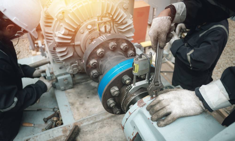 A team of maintenance technicians service a large mechanical power generation motor with wrenches and other repair tools.