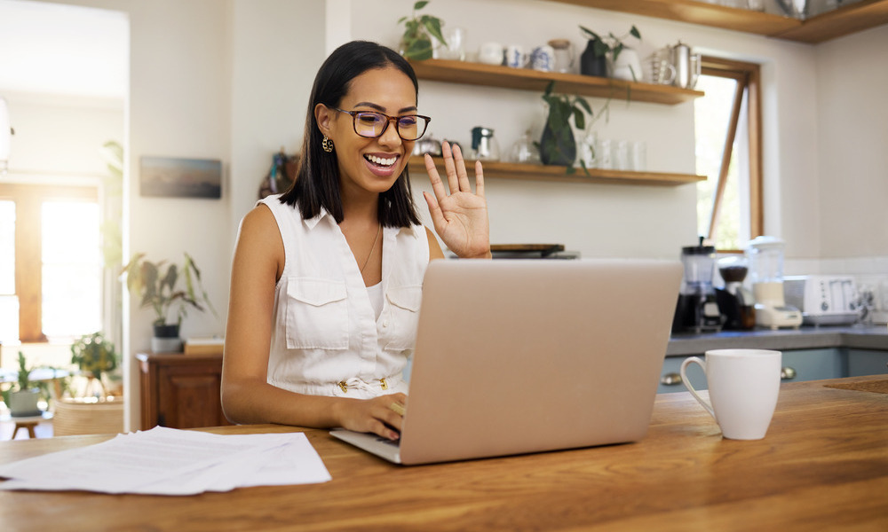 A young remote worker on a conference call with her digital team, sitting in her dedicated home office space.