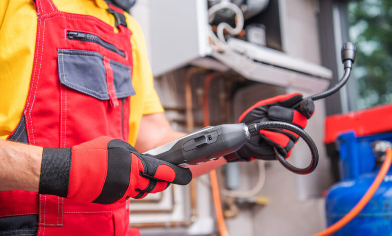 A person wearing red overalls and a yellow shirt is using a black and gray device. The background is blurry.