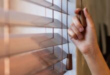 A homeowner holding onto their window treatment pulley cord. They are adjusting the settings on the window blinds.