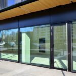 The front of a commercial building, made up entirely of large, floor-to-ceiling glass windows and a glass door.