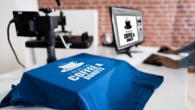 A blue t-shirt draped over a white table that says, "I run on coffee and donuts." The computer next to it says the same thing.