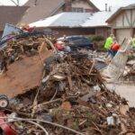 A pile of debris, including tree branches and demolished structures, in a neighborhood after a tornado has hit.
