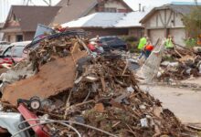 A pile of debris, including tree branches and demolished structures, in a neighborhood after a tornado has hit.