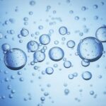 Close-up of large bubbles in blue water. The bubbles have bubbles inside themselves, and smaller ones are in the background.