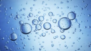 Close-up of large bubbles in blue water. The bubbles have bubbles inside themselves, and smaller ones are in the background.