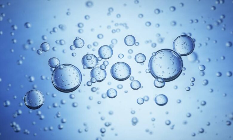 Close-up of large bubbles in blue water. The bubbles have bubbles inside themselves, and smaller ones are in the background.