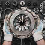 Close-up of a pair of hands holding up a used clutch basket. The person is wearing white and blue gloves on their hands.