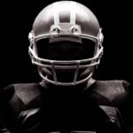 An American football athlete wearing his full team uniform, including his sporting helmet and football jersey.