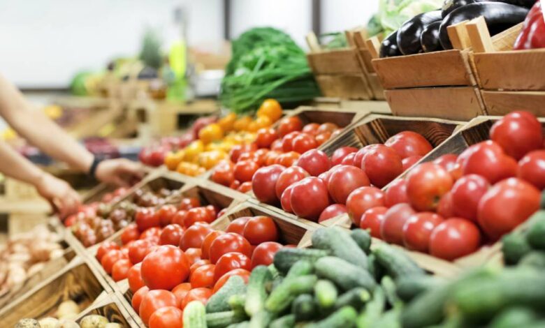 A close-up view shows a display of various fresh vegetables, including tomatoes, zucchini, and potatoes.