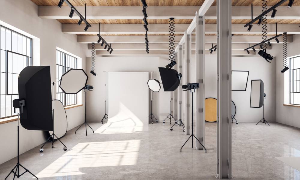 A large open concept photography studio with natural light pouring in and equipment scattered around.