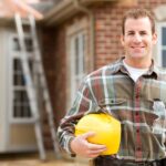 A friendly-looking general contractor standing outside of his client’s home, smiling and posing for a picture.