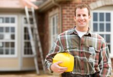 A friendly-looking general contractor standing outside of his client’s home, smiling and posing for a picture.