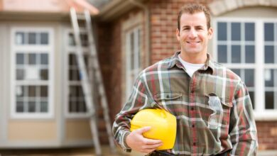 A friendly-looking general contractor standing outside of his client’s home, smiling and posing for a picture.