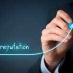 An executive's hand with a pen writes the word "reputation" and an arrow showing it trending upward.