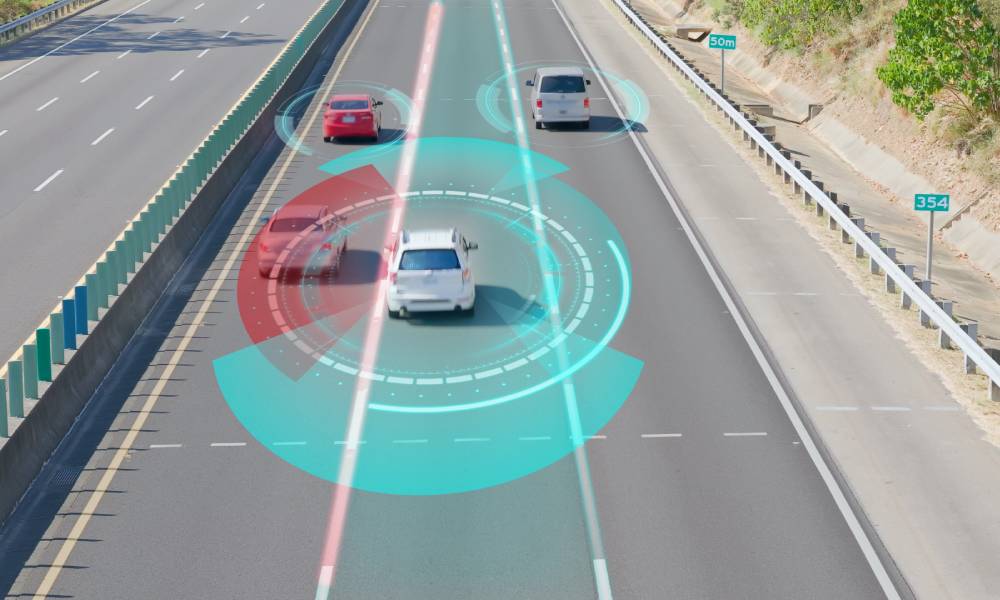 A vehicle driving down a three-lane highway. The vehicle features LiDAR technology and has red and blue graphics.