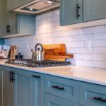 A newly renovated kitchen with white subtile backsplash, a gas stove cooktop, and blue-painted cabinetry.
