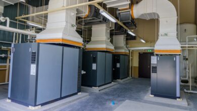 A well-organized facility with four large, gray, industrial air compressor machines with white piping coming out of them.