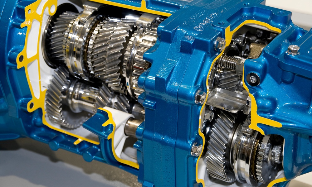 An industrial gearbox that's cut open showing the gears and connections. The gearbox is blue plated with yellow accents.