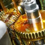 An industrial manufacturing facility with a moving gear covered in food-grade lubricant. The lubricant is honey-colored.