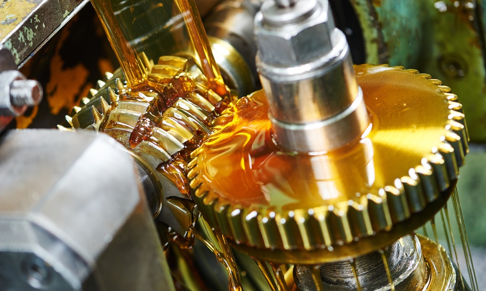 An industrial manufacturing facility with a moving gear covered in food-grade lubricant. The lubricant is honey-colored.