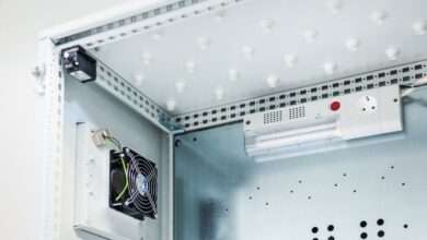 A metal enclosure houses a fan and an electric lamp mounted against smooth white interior surfaces.