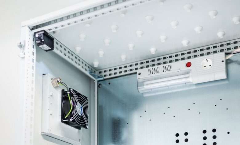 A metal enclosure houses a fan and an electric lamp mounted against smooth white interior surfaces.