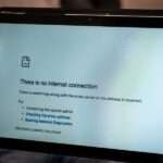 A close-up of someone's hand holding a tablet with a screen saying that there's no internet connection.