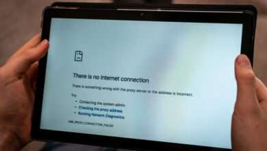 A close-up of someone's hand holding a tablet with a screen saying that there's no internet connection.