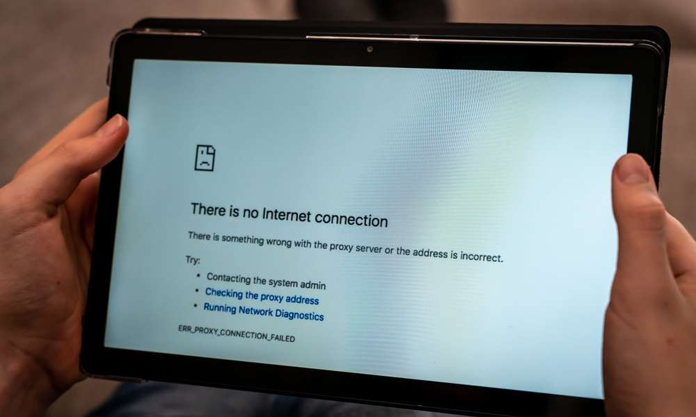 A close-up of someone's hand holding a tablet with a screen saying that there's no internet connection.