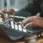 A digital illustration shows the words "Cost reduction" while a person's hands work on a laptop in the background.