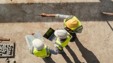 Above the heads of three engineers looking at a laptop on a construction site. They are all wearing hard hats.