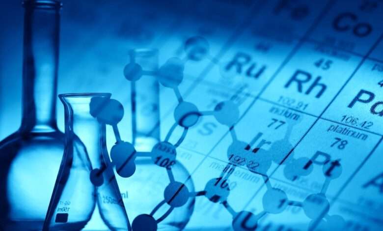 A molecular structure is superimposed over a periodic table of elements and the outlines of glass beakers and flasks.