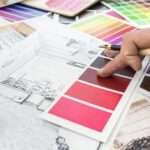 A close-up of a home designer working at the office, a house sketch with a color catalog for a renovation project.