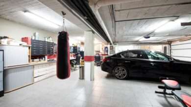 A black car is parked in a well-organized garage with a white tiled floor, exercise equipment, and storage solutions.