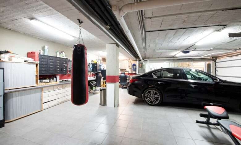 A black car is parked in a well-organized garage with a white tiled floor, exercise equipment, and storage solutions.