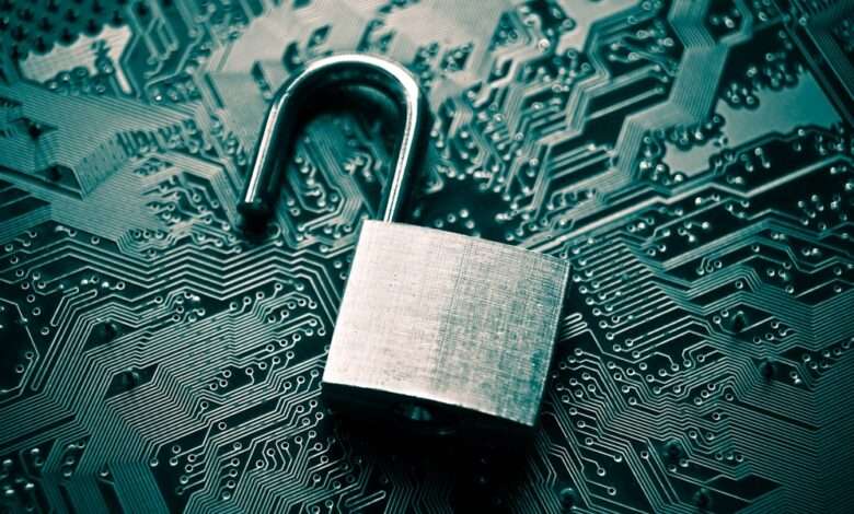 There is an unlocked padlock resting on top of a circuit board. The padlock has a rough finish.