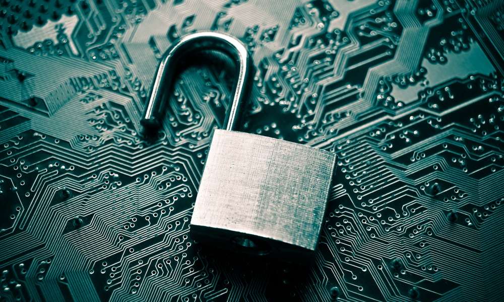 There is an unlocked padlock resting on top of a circuit board. The padlock has a rough finish.