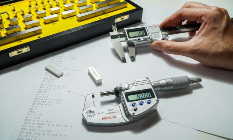 Someone holds a digital micrometer next to a digital caliper. A yellow case holds gauge blocks.