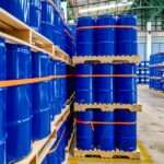 A warehouse full of blue chemical drums stacked on wooden pallets. The drums are brand new and shiny.