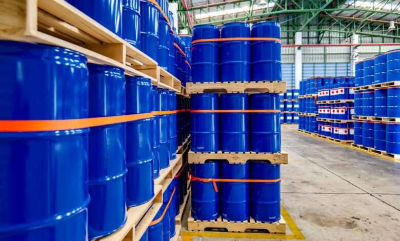 A warehouse full of blue chemical drums stacked on wooden pallets. The drums are brand new and shiny.