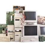 Collection of vintage computer hardware including towers, monitors, keyboards, and loose motherboards on white background.