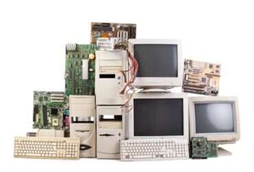 Collection of vintage computer hardware including towers, monitors, keyboards, and loose motherboards on white background.