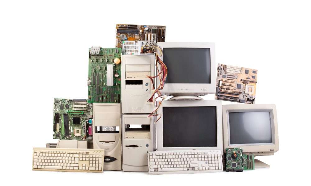 Collection of vintage computer hardware including towers, monitors, keyboards, and loose motherboards on white background.
