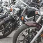 A close-up of several motorcycles parked in a neat row. Each bike is a different color and has a different front-end style.